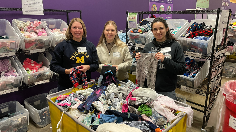 Three employees sorting clothes while volunteering
